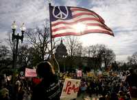 Un manifestante agita en Washington una bandera estadunidense con el símbolo de la paz.