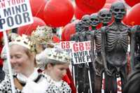 Manifestantes vestidos de reyes cerca de esculturas que semejan personas afectadas por el hambre recorren las calles de Rostock, Alemania, durante una protesta contra el G-8