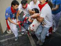 Pariticipantes en el encierro de ayer, en Pamplona, auxilian al mexicano que resultó herido por un toro