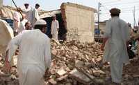 Paquistaníes de Miran Shah, área tribal en la frontera con Afganistán, recogen los escombros de una tienda y un puesto de seguridad destruidos por militantes islámicos
