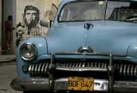 Un auto antiguo estacionado cerca de una pinta de Ernesto Che Guevara en La Habana, ciudad que se prepara para conmemorar el 54 aniversario del asalto al cuartel Moncada