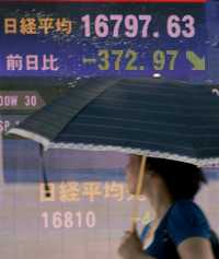 Un peatón pasa delante de un tablero electrónico de la bolsa de valores de Tokio. El viernes el banco de Japón inyectó un trillón de yenes (8 mil 400 millones de dólares) y el índice Nikkei bajó 365.40 puntos, 2.13 por ciento
