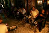 Debido al corte de energía eléctrica en la franja de Gaza, los palestinos asistentes a un café, fuman y conversan a la luz de algunas velas y lámparas de propano. Israel cortó el suministro de combustible la semana pasada