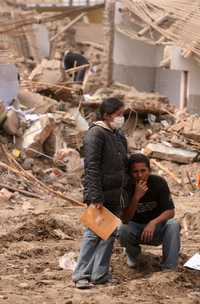 Residentes de Pisco, una de las ciudadas más devastadas por el terremoto, entre los escombros de lo que fue su casa