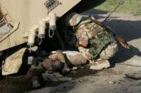 Un soldado iraquí intenta sacar de abajo de un vehículo el cuerpo de un camarada muerto cerca de la ciudad de Baquba