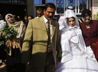 Mazen Mahmod, de 35 años, y Sarah Abbas, de 17, salen de la casa paterna de la novia para casarse en el barrio chiíta de Ciudad Sadr