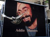 Una paloma pasa frente a una pantalla gigante que se colocó en la plaza central de Módena, donde se efectuaron los funerales del tenor Luciano Pavarotti