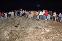 Reporteros y rescatistas observan el cráter de 30 metros de diámetro y tres de profundidad que dejó la explosión ocurrida el domingo en Monclova, Coahuila