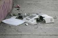 Peritos observan los restos del aparato telefónico que fue destrozado con un juego pirotécnico en la colonia Insurgentes Cuicuilco