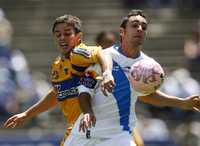 El jugador de los Tigres, Lucas Ayala, disputa el balón con Pablo Aja, quien hizo su debut ayer en el estadio Cuauhtémoc
