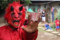 Un diablo de la cuadrilla de tecomates muestra un billete recibido para la ofrenda después de danzar en una casa de Cuatenahuatl