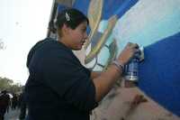 Sandra Vega realiza su obra en la barda perimetral del Estadio Azteca