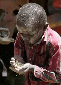 Uun niño recoge granos del suelo en Nairobi