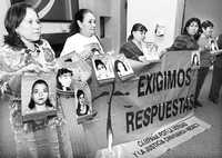 Madres de mujeres asesinadas o desaparecidas en Ciudad Juárez muestran pancartas con las fotos de sus familiares, luego de una reunión con el relator de la CIDH, en abril de 2007
