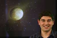 El científico español Ignasi Ribas abajo de una fotografía simulada del pequeño planeta