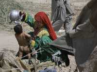 Una afgana baña a su niño cerca de su tienda. La mujer escapó de su pueblo cuando militantes del talibán asumieron el control del distrito de Arghandab, en la provincia de Kandahar, hacia el sur de Kabul