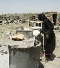 Más de 40 familias chiítas, desplazadas por los frecuentes combates en el sur de Bagdad, viven desde hace unos dos años en basureros. En la imagen, una mujer hornea su pan en Abu Dsheer