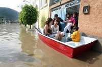 Más de 200 familias de Ixtapaluca resultaron afectadas por el desbordamiento del canal de aguas negras Guadalupe Victoria. En la imagen, bomberos ayudan a un grupo de colonos a salir de su vivienda