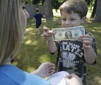 Un pequeño muestra un dólar a su madre en Maple Valley, Washington, cerca de Seattle