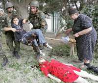 Soldados georgianos auxilian a un niño herido, en tanto su madre yace muerta,en la localidad de Gori, a 8 kilómetros de Tbilisi, la capital