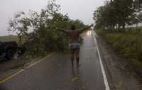 Un dominicano pide ayuda en la carretera cerca de Higuey después de chocar su auto contra un árbol derribado por la tormenta tropical Fay