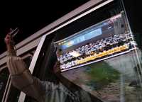 Un pasajero del transporte público toma una fotografía a la pantalla gigante, reflejada en la ventana del autobús, donde se transmitió en vivo el lanzamiento de la misión ShenZhou VII  del Centro Espacial Jiuquan