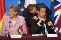El primer ministro italiano, Silvio Berlusconi, habla con el presidente de Francia, Nicolas Sarkozy, durante una conferencia de prensa tras una reunión de mandatarios europeos en la que se discutió la actual crisis financiera mundial. A su lado, la canciller alemana, Angela Merkel