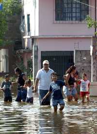 Una familia sale de su vivienda inundada por el desbordamiento del río Mezcalapa, en Río Viejo, municipio de Centro
