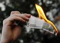 Un manifestante quema un billete de cinco euros durante una protesta efectuada ayer en el centro de Madrid, contra el capitalismo depredador y la cumbre financiera del G-20
