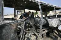 Civiles revisan los restos de un autobús destruido en Bagdad por uno de los cuatro bombazos perpetrados ayer en Irak