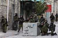 Soldados israelíes toman posiciones durante un enfrentamiento con manifestantes palestinos en Hebrón, Cisjordania, después de los bombardeos sobre Gaza