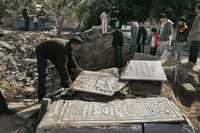 Palestinos reparan las tumbas de sus familiares, destrozadas durante un ataque israelí contra el cementerio Sheik Radwan de la ciudad de Gaza