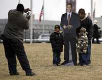 Un hombre posa con sus nietos junto a una figura de Barack Obama en un parque de Washington