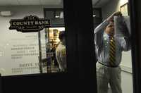 Un empleado pega un aviso de cierre del County Bank en Merced, California